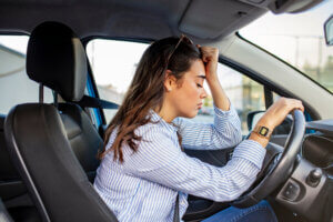 Woman Holding her Head behind the Steering Wheel